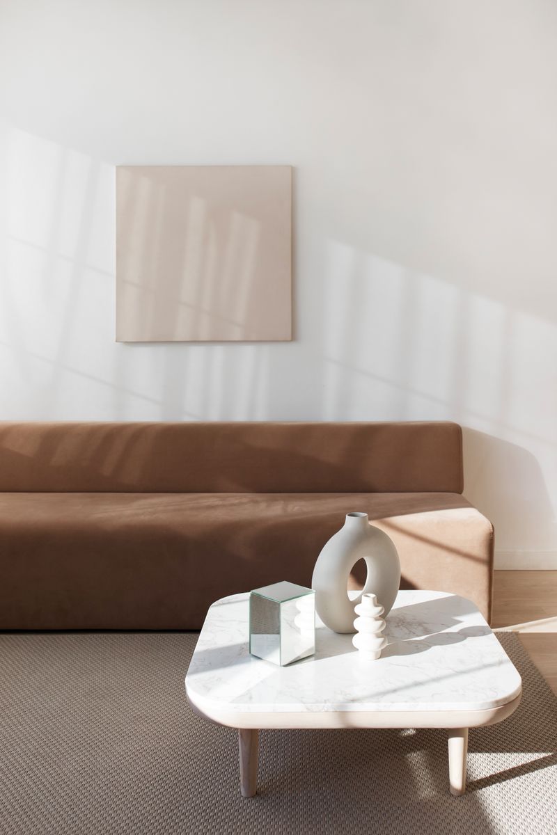 a minimalist living space with a few carefully chosen furniture pieces, soft natural light, warm col