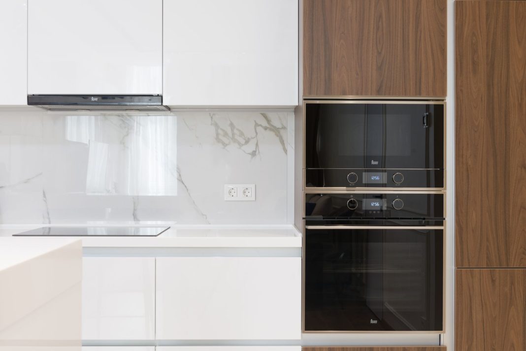 A tidy, minimalist kitchen with natural light pouring in, showcasing a clean countertop with a few e