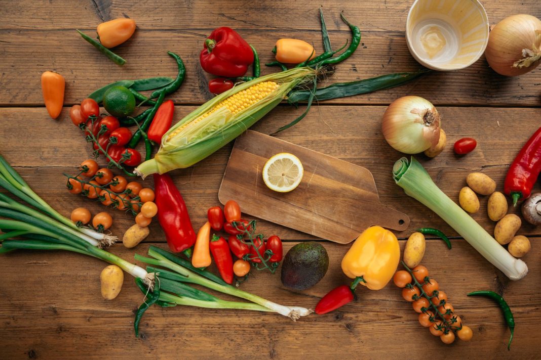 An inviting kitchen scene with fresh, colorful vegetables on a wooden countertop, sunlight streaming