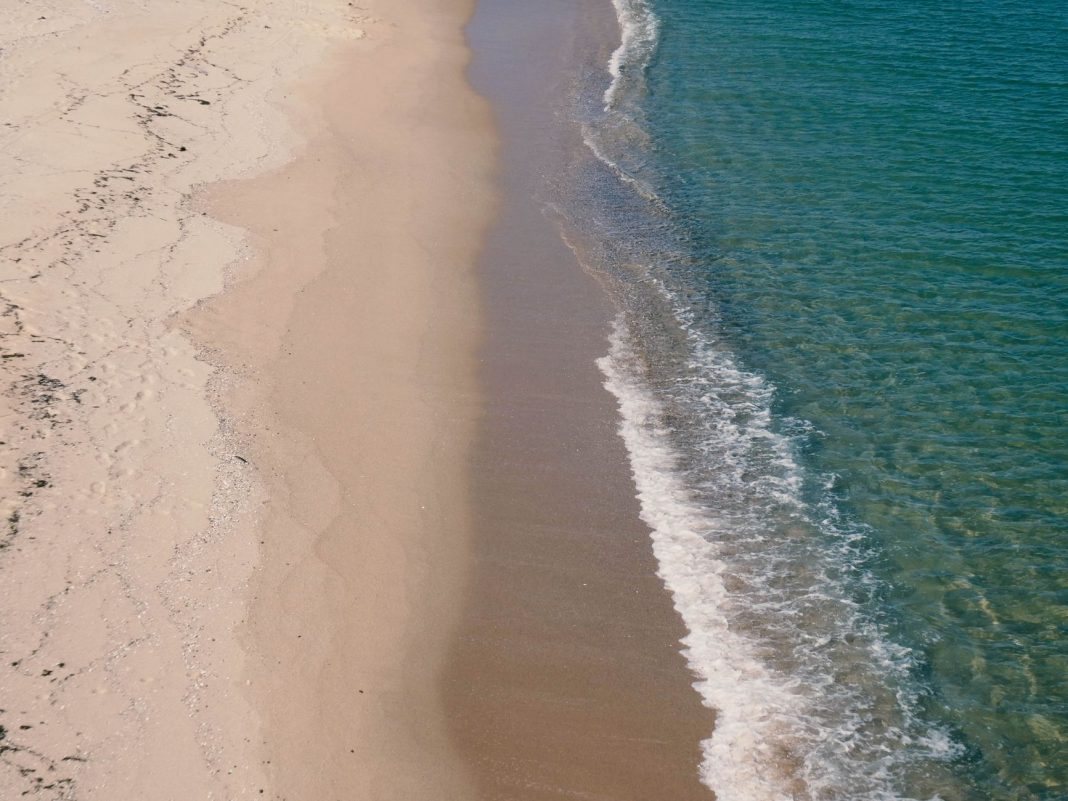 A serene landscape of a clean beach with no litter, showcasing the beauty of nature, bright blue sky