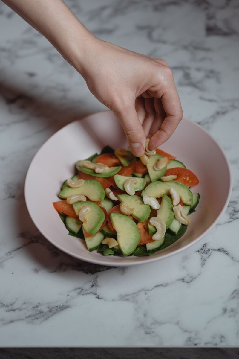A person enjoying a bright raw food salad in a cozy café, surrounded by lush greenery, sunlight streaming in, capturing the joyful moment of eating healthfully, warm color palette, photojournalistic style